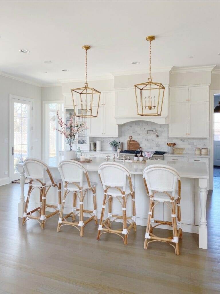 White kitchen with white rattan chairs at kitchen island