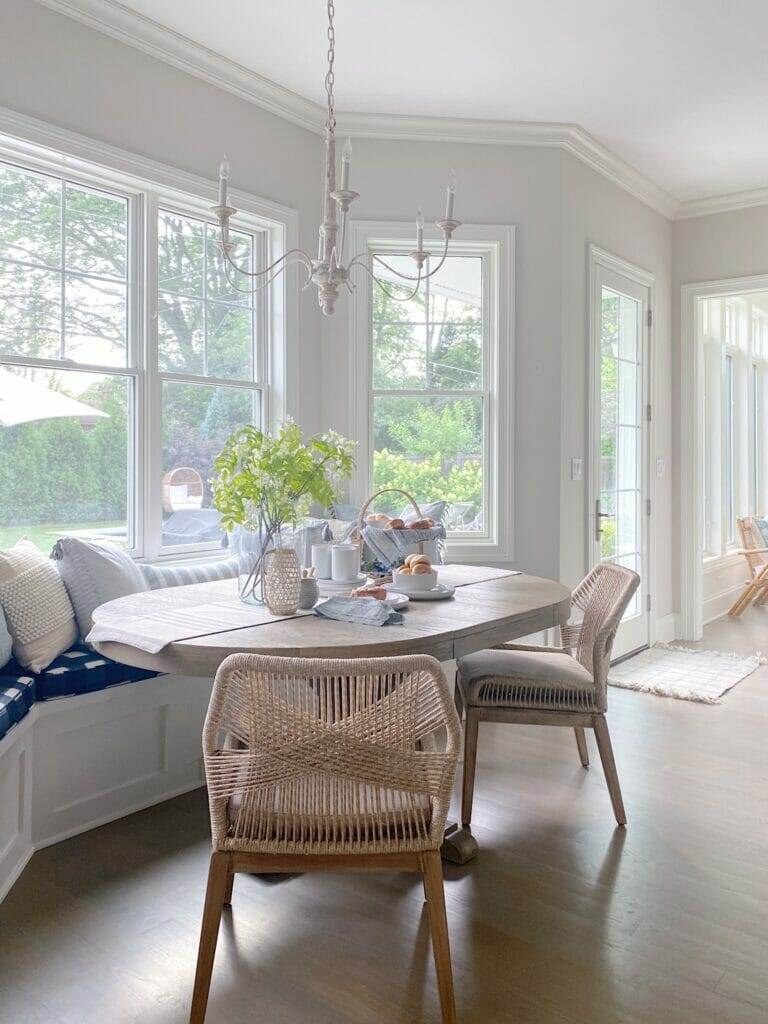 Kitchen banquette featuring Gap Home kitchen pieces and pretty affordable pillows, woven chairs, Benjamin Moore classic gray walls.