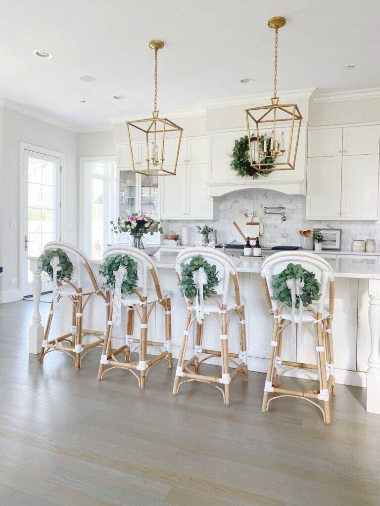 Life On Cedar Lane Holiday Shopping Guide | Christmas kitchen with eucalyptus wreaths on counter stool backs, faux wreath on kitchen hood