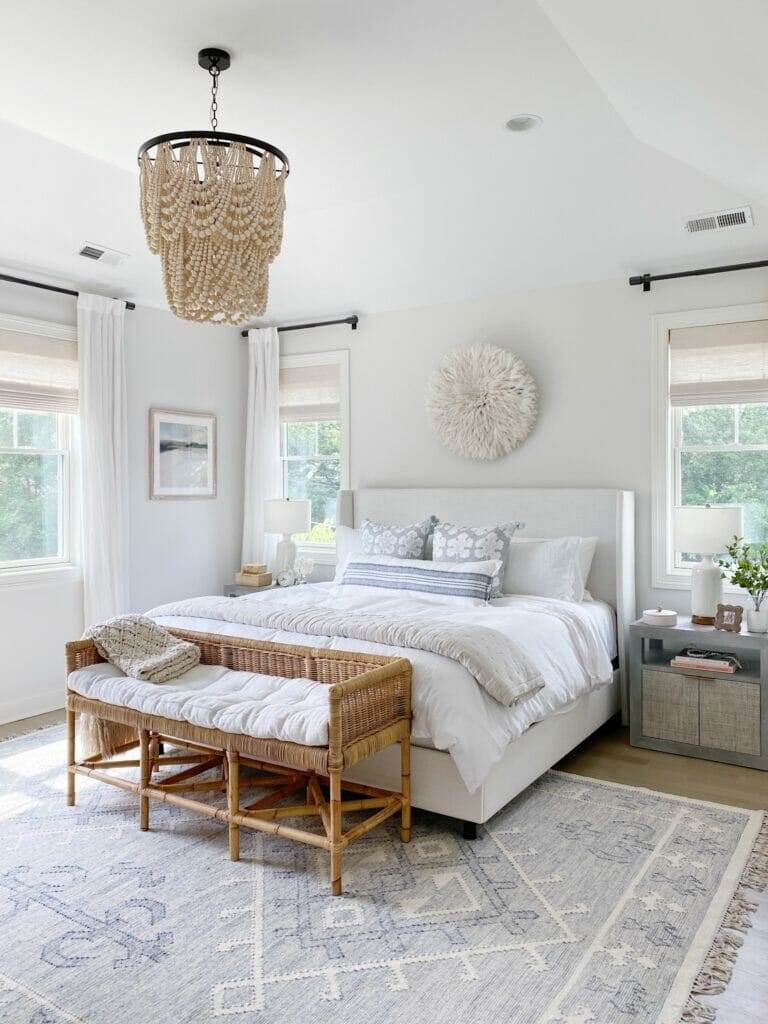coastal inspired bedroom coastal inspired bedroom features upholstered bed, woven rattan nightstands, Serena & Lily alamere rug, and beaded chandelier