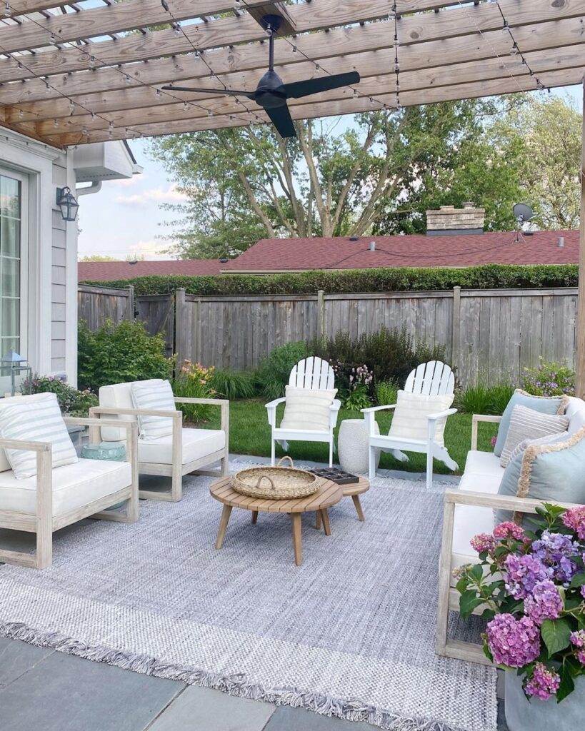 outdoor seating area outdoor seating area with chairs, and couch with neutral color cushions and pillows with a blue and white printed outdoor rug